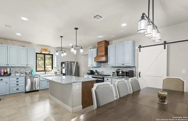 a large kitchen with kitchen island a large counter top space a sink stainless steel appliances and cabinets