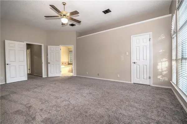 an empty room with chandelier fan and windows