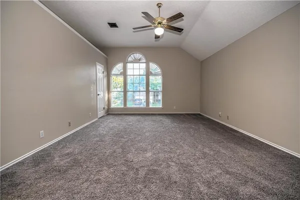 an empty room with windows and ceiling fan