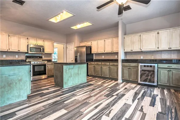 a kitchen with stainless steel appliances kitchen island granite countertop a stove top oven a sink and a microwave