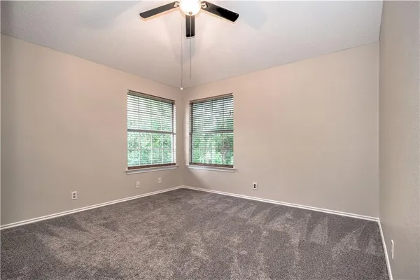 an empty room with a window and a ceiling fan