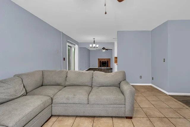 an empty room with a chandelier fan and windows