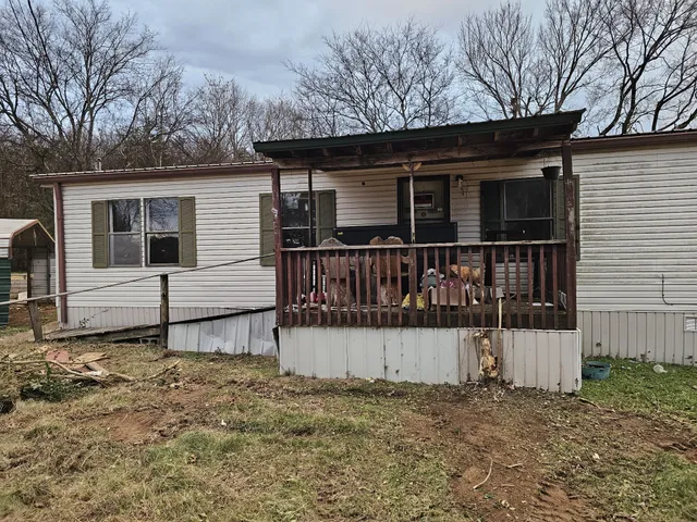 a white house that has a small yard and large trees