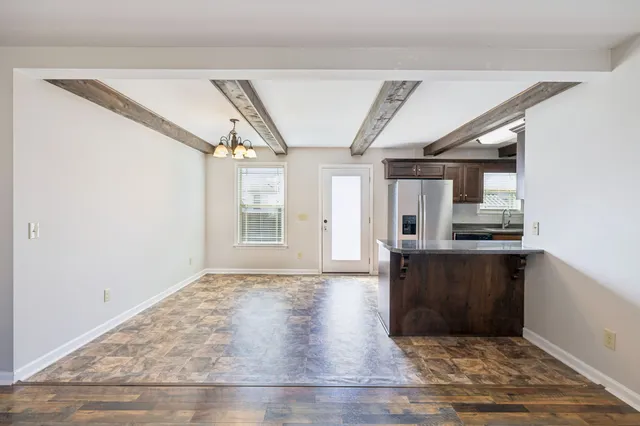 a view of empty room with wooden floor and kitchen view