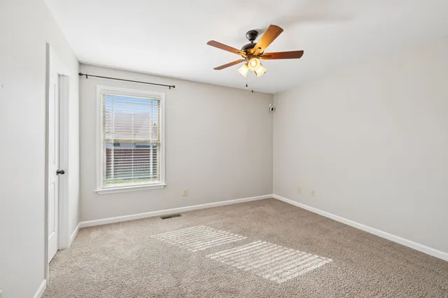 an empty room with a window and a fan