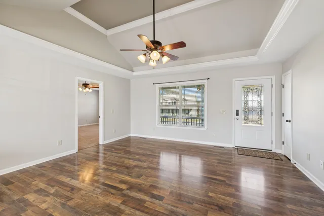 a view of an empty room with window and wooden floor