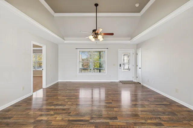 a view of an empty room with window and wooden floor