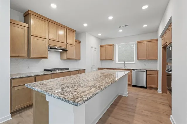 a kitchen with stainless steel appliances granite countertop a sink stove and refrigerator