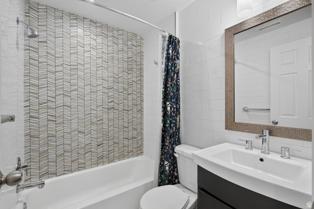 2223 North Pointe Meadow Loop Lehi, UT 84048 - Photo 31 of 56 Bathroom featuring a tub/shower combination with a chevron-patterned tile surround, a single-handle shower head, a chrome shower rod, a wall-mounted vanity with an integrated sink, and a framed mirror