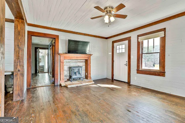 an empty room with chandelier fan and windows
