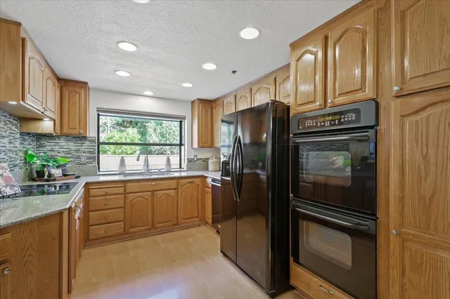 a kitchen with stainless steel appliances granite countertop a refrigerator a stove and a sink