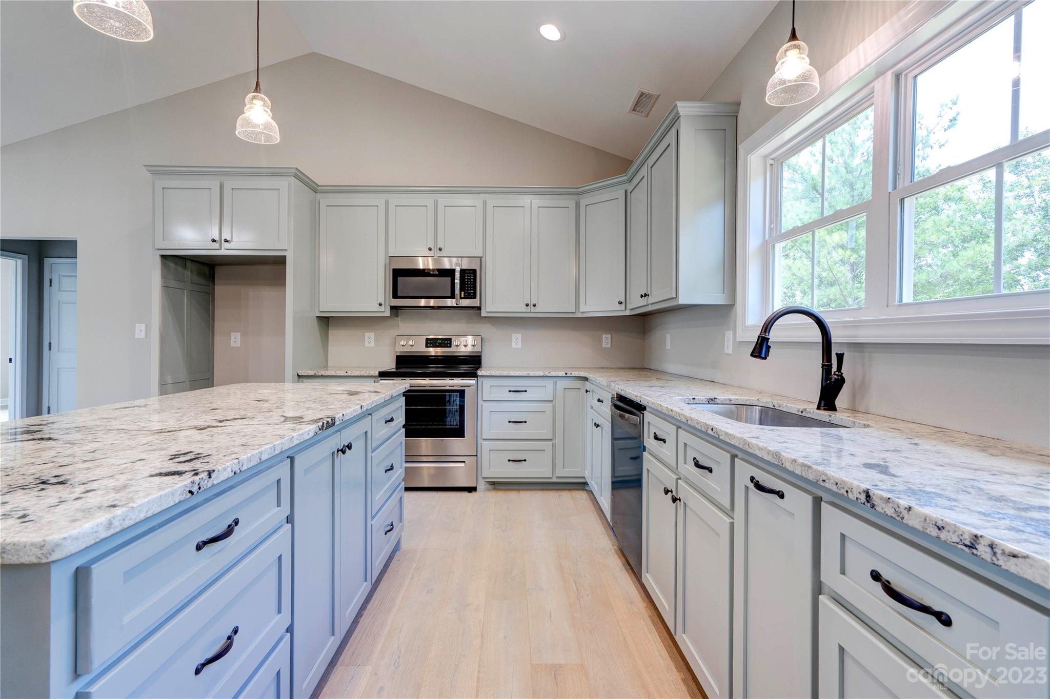 4326 Boulder Drive Morganton, NC 28655 - Photo 12 of 46 a kitchen with kitchen island granite countertop a sink appliances cabinets and a large window