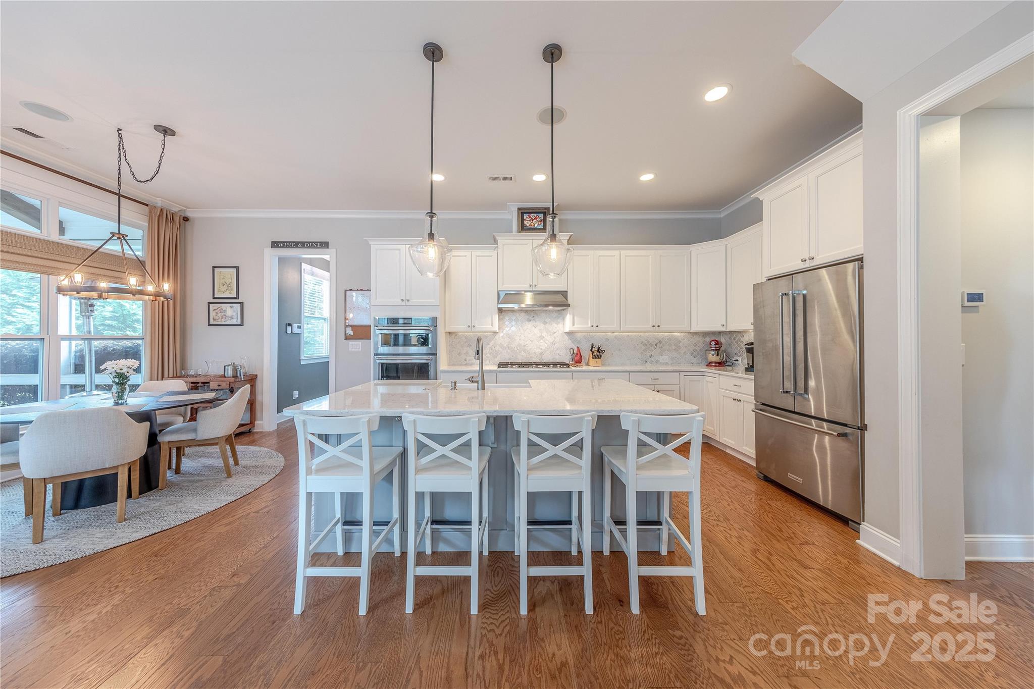 5256 Meadowcroft Way Fort Mill, SC 29708 - Photo 9 of 48 a kitchen with stainless steel appliances granite countertop a dining table chairs refrigerator and wooden floor