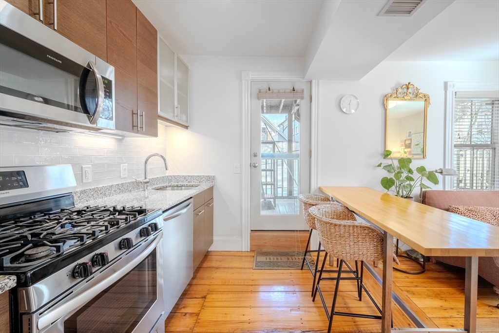 20 Porter Street, Unit 2 Boston, MA 02130 - Photo 4 of 35 a kitchen with stainless steel appliances granite countertop a stove a sink dishwasher and microwave with wooden floor