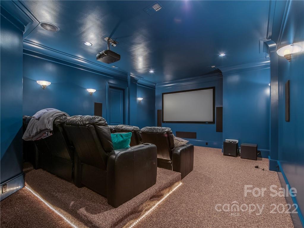 14140 Claysparrow Road Charlotte, NC 28278 - Photo 39 of 48 a projector room with large couches and projector with kitchen view