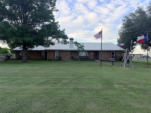 a front view of a house with a garden and trees