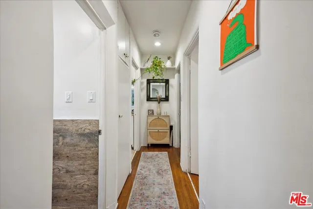 a view of a hallway with wooden floor and a bathroom