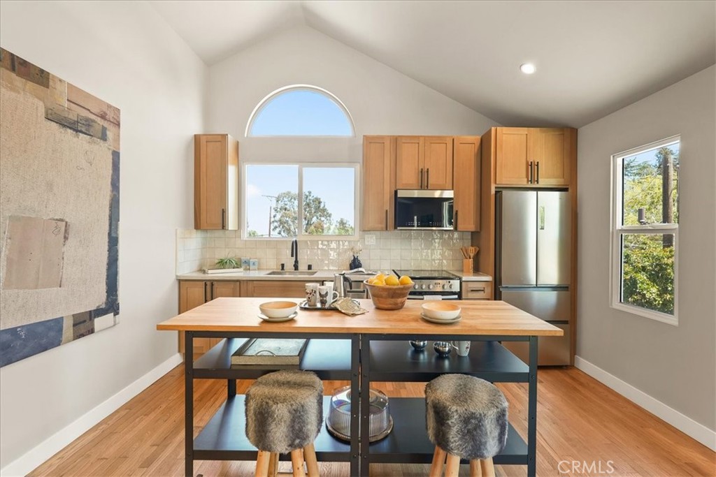 7404 Woodrow Wilson Drive Los Angeles, CA 90046 - Photo 44 of 57 a kitchen with stainless steel appliances granite countertop a sink a stove a refrigerator with a dining table and chairs