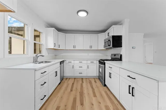 a kitchen with granite countertop white cabinets white stainless steel appliances with a sink and dishwasher