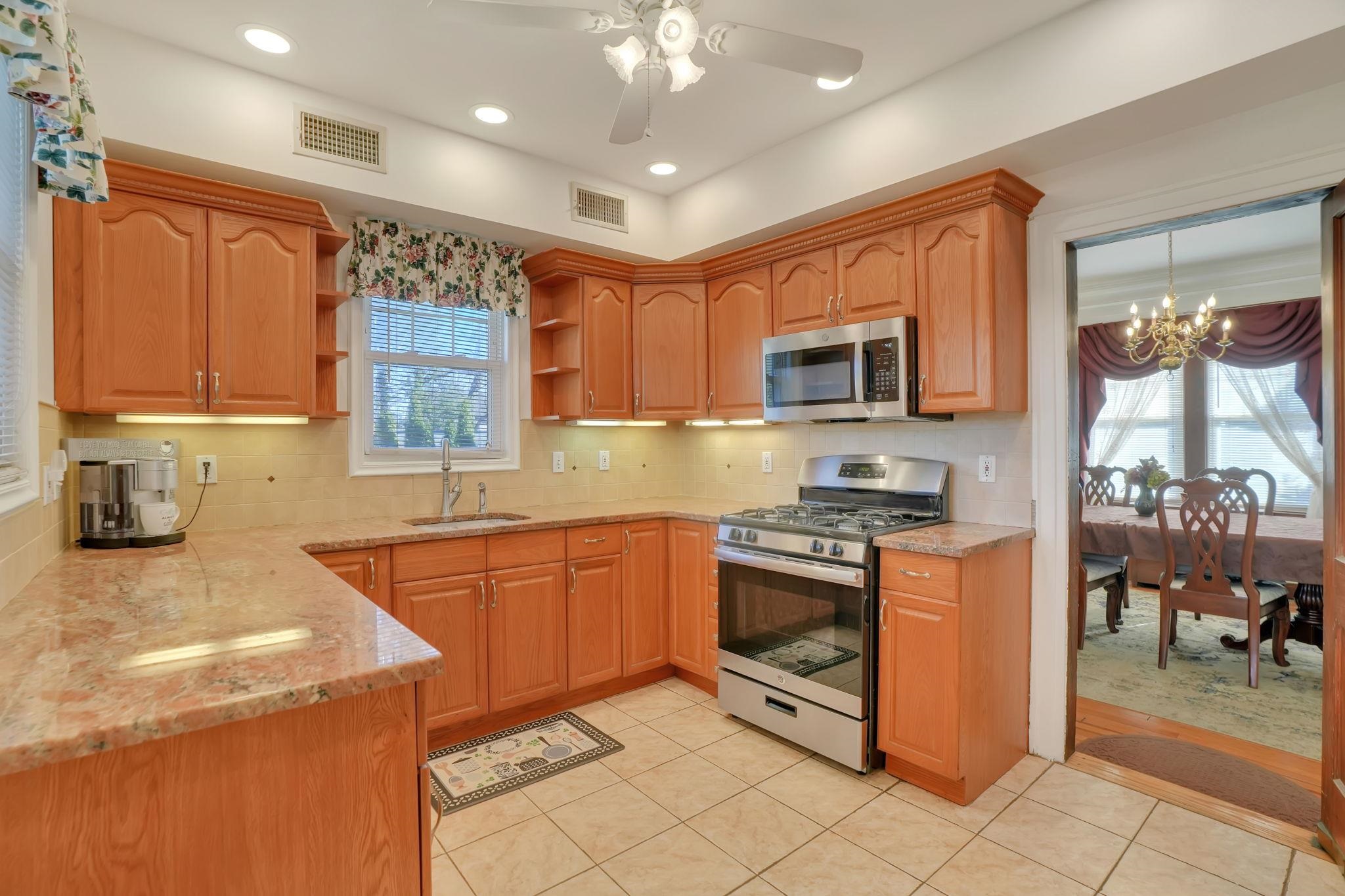 10 Lynn Court Rutherford, NJ 07070 - Photo 6 of 37 a kitchen with stainless steel appliances granite countertop a stove top oven a sink dishwasher a dining table and chairs with wooden floor