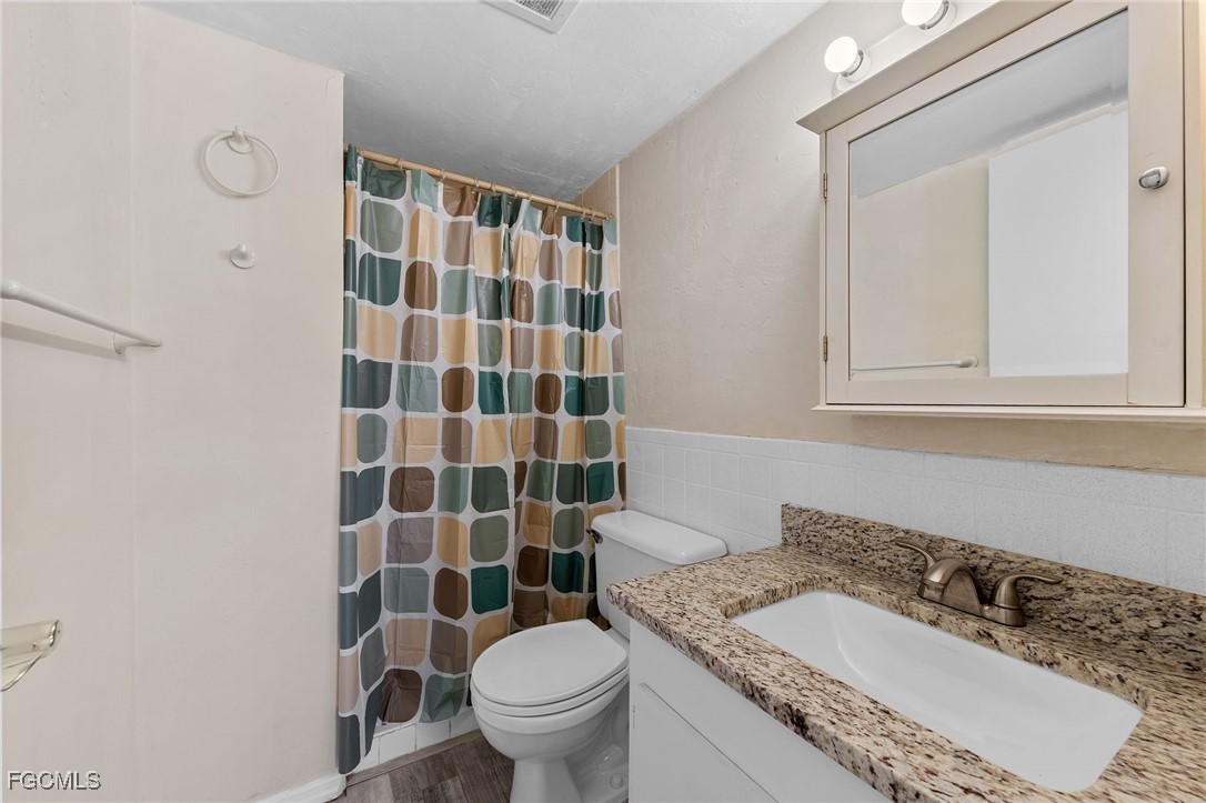 2828 Jackson Street, Unit D8 Fort Myers, FL 33901 - Photo 24 of 37 a bathroom with a granite countertop sink a toilet and a mirror