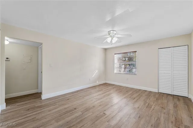 an empty room with wooden floor chandelier fan and windows