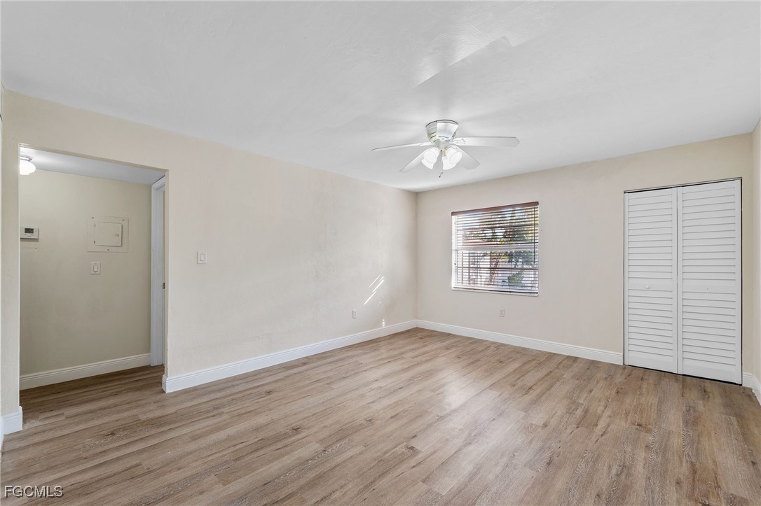 2828 Jackson Street, Unit D8 Fort Myers, FL 33901 - Photo 5 of 37 an empty room with wooden floor chandelier fan and windows