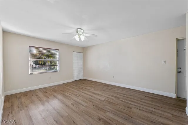 a view of an empty room with a window and wooden floor