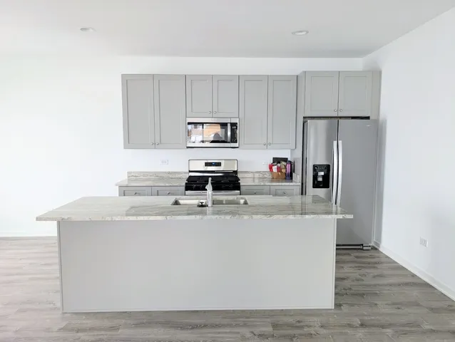 a living room with stainless steel appliances a sink a stove a refrigerator cabinets and a counter top space