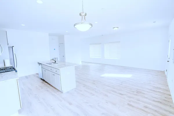 a view of an empty room with a sink and wooden floor