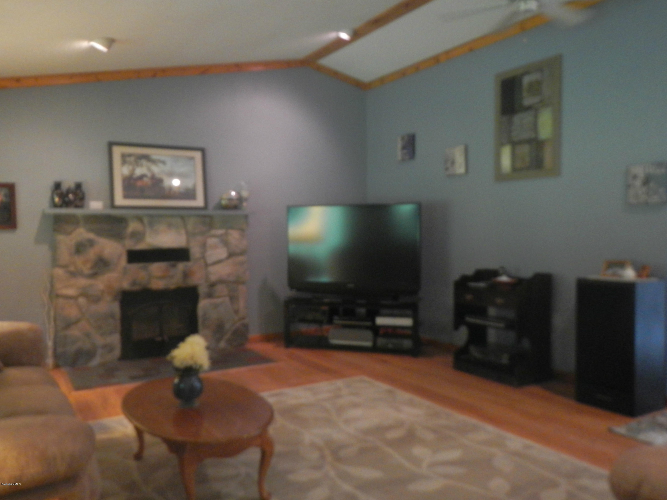 99 Strykers Road Florida, MA 01247 - Photo 8 of 26 a living room with furniture a flat screen tv and a fireplace