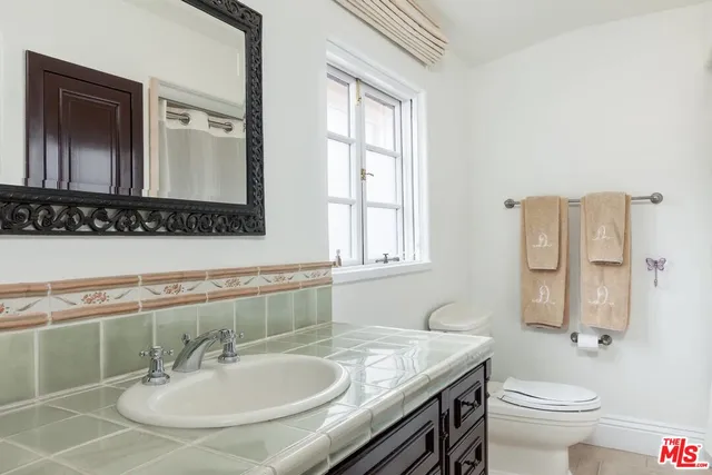 a bathroom with a granite countertop sink a toilet and a mirror