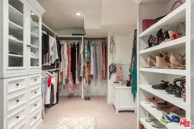 a view of walk in closet with clothes and shoes