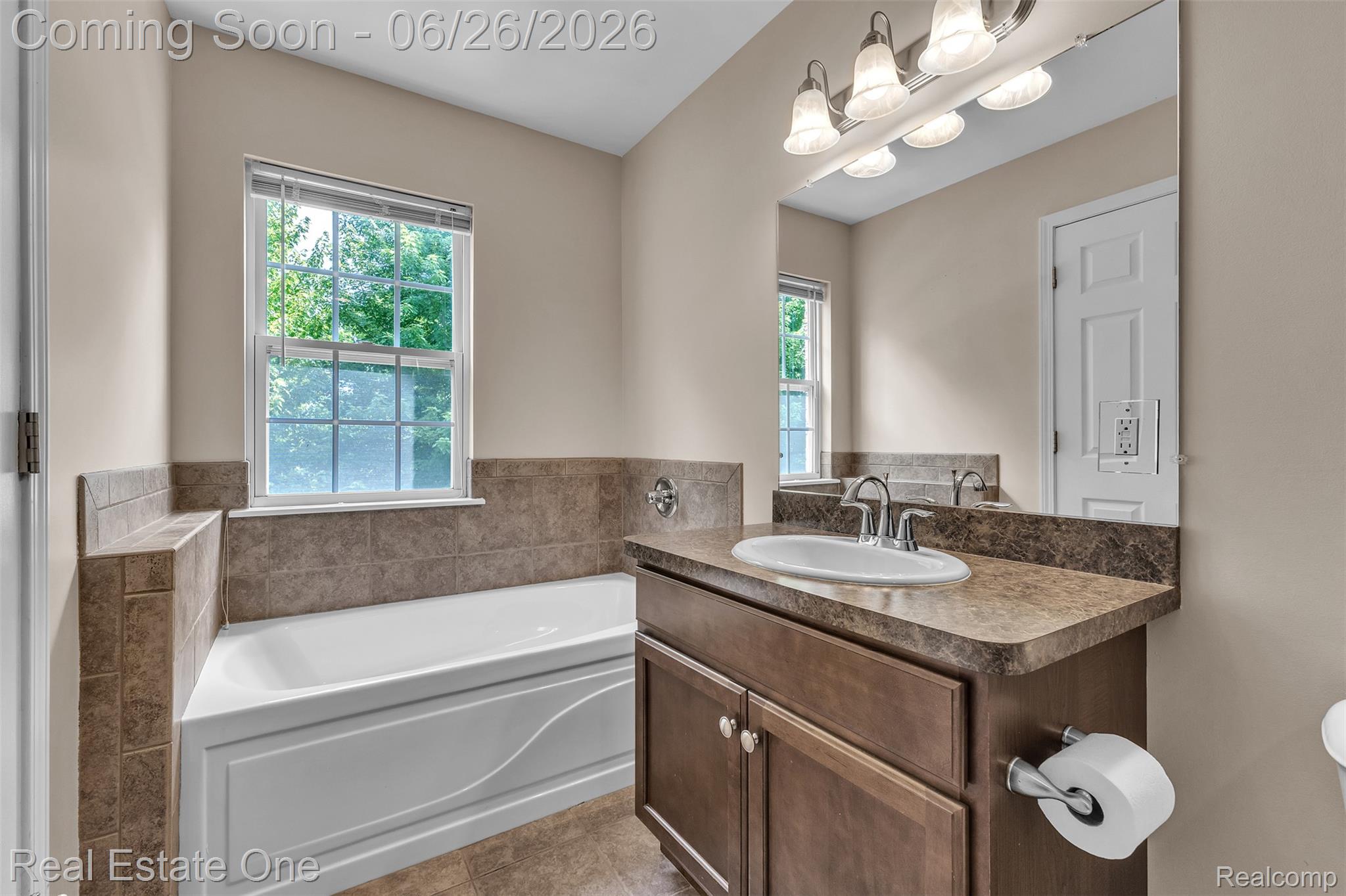 41590 Mitchell Road Novi, MI 48377 - Photo 33 of 45 Bathroom featuring a built-in tub with tile surround, a single vanity with a laminate countertop, a large wall mirror, and a window with blinds