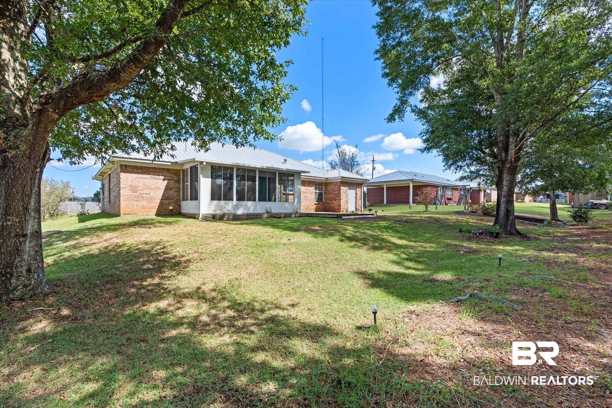 16216 Pointer Drive Foley, AL 36535 - Photo 20 of 21 Rear exterior featuring a brick facade, screened porch, and metal roof