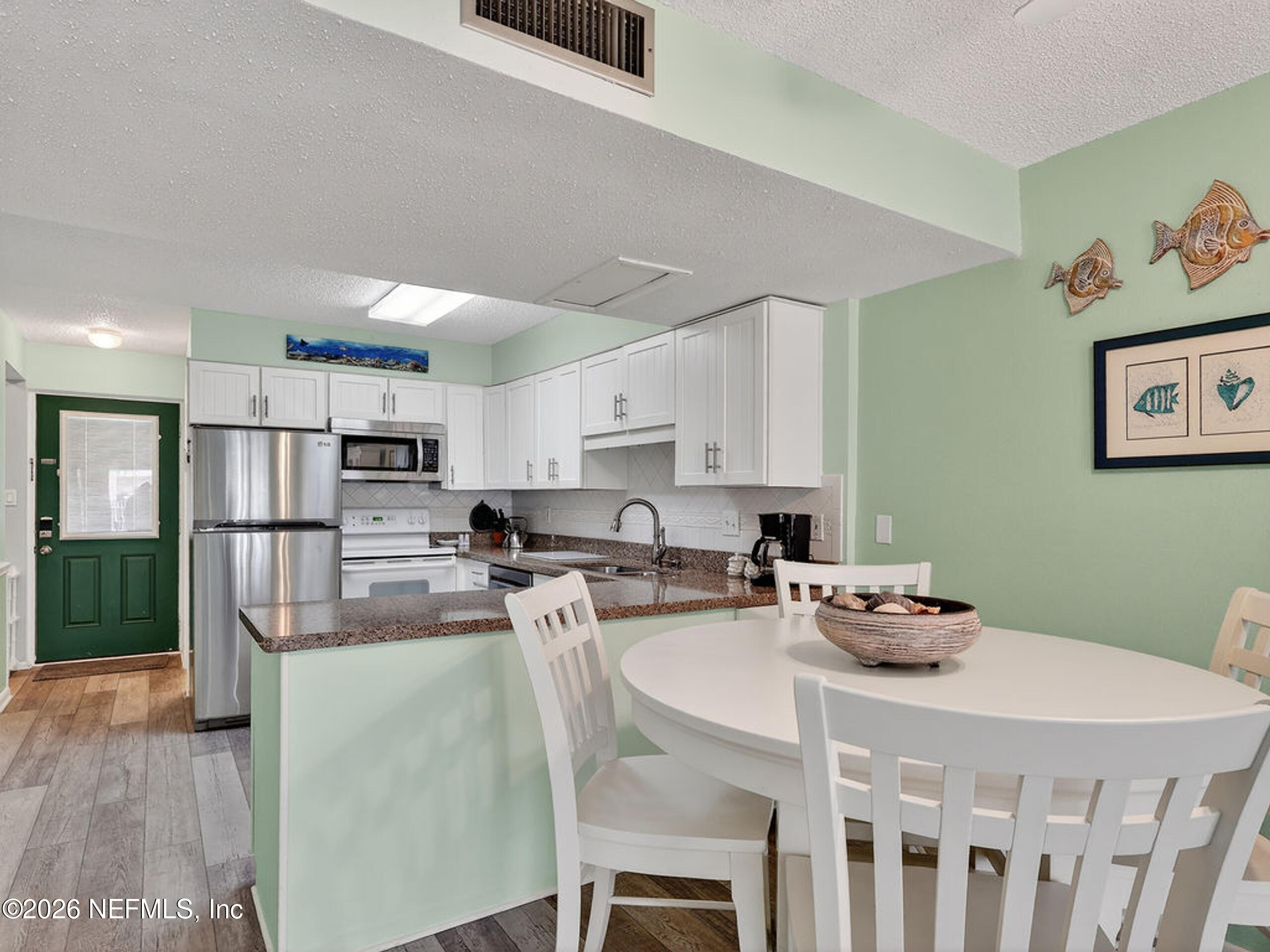 1 Ocean Trace Road, Unit 230 St. Augustine Beach, FL 32080 - Photo 9 of 50 a kitchen with kitchen island a stove a table and chairs