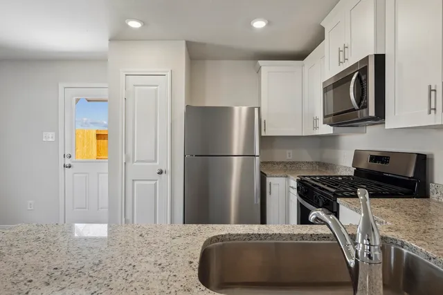 a view of a kitchen with a sink a ceiling fan and wooden floor