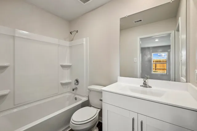 a bathroom with a bathtub shower sink vanity mirror and toilet