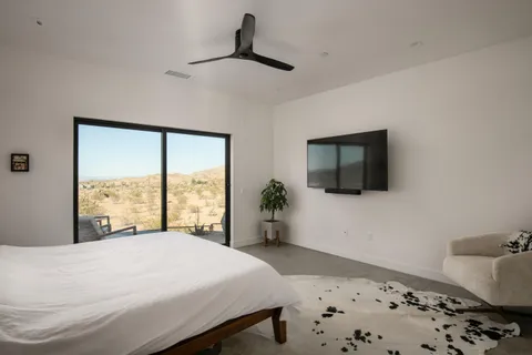 a bedroom with a large bed and a flat tv screen on dresser