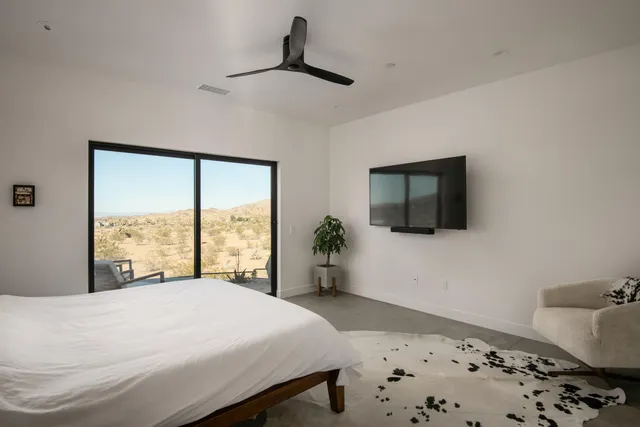 a bedroom with a large bed and a flat tv screen on dresser