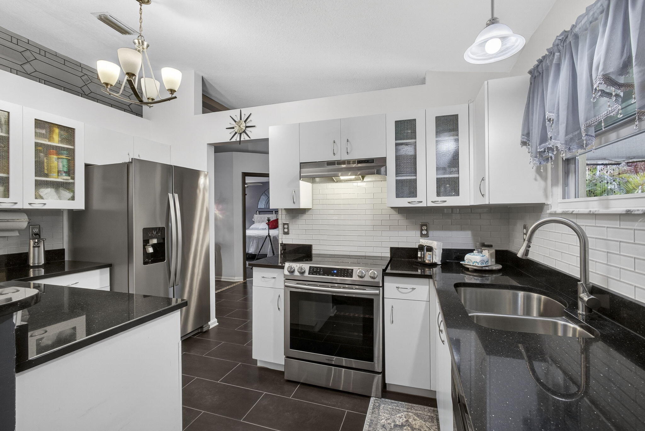 15773 85th Road North Loxahatchee, FL 33470 - Photo 21 of 75 a kitchen with stainless steel appliances granite countertop a sink stove a refrigerator cabinets a dining table and chairs with wooden floor