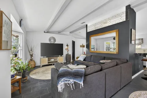 a living room with furniture a rug a lamp and a large window