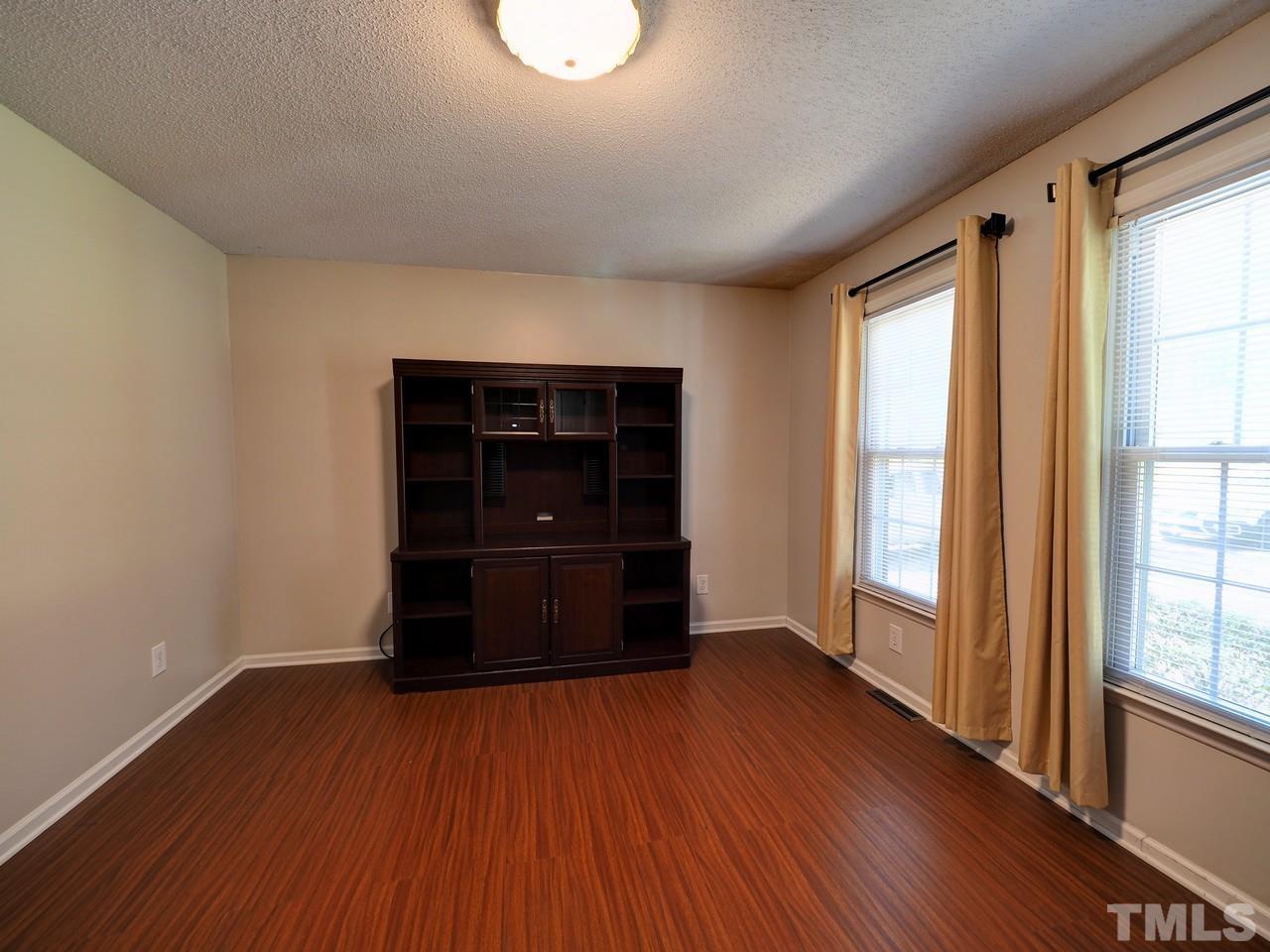 8329 Bells Lake Road Apex, NC 27539 - Photo 13 of 26 an empty room with wooden floor and windows