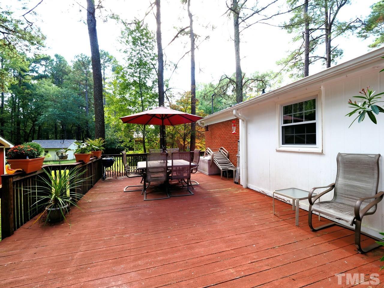 8329 Bells Lake Road Apex, NC 27539 - Photo 21 of 26 a view of a patio with table and chairs under an umbrella with wooden fence