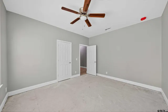 an empty room with windows and fan