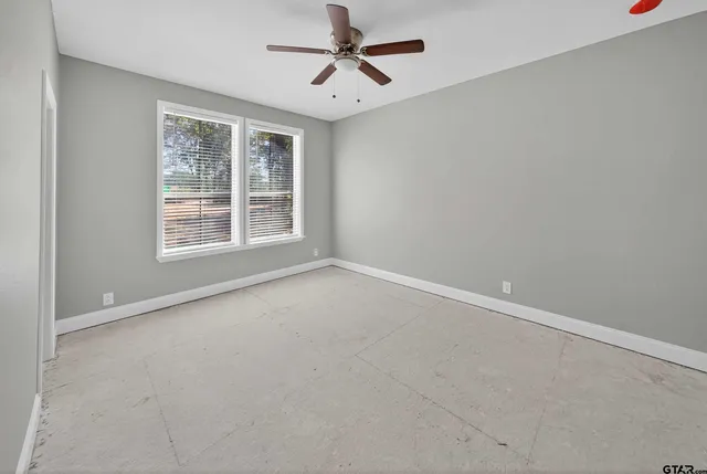 an empty room with windows and fan