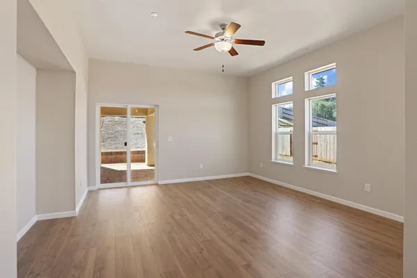 a view of an empty room with a window and wooden floor