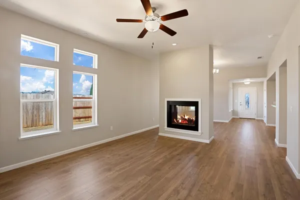 a view of an empty room with a window and wooden floor