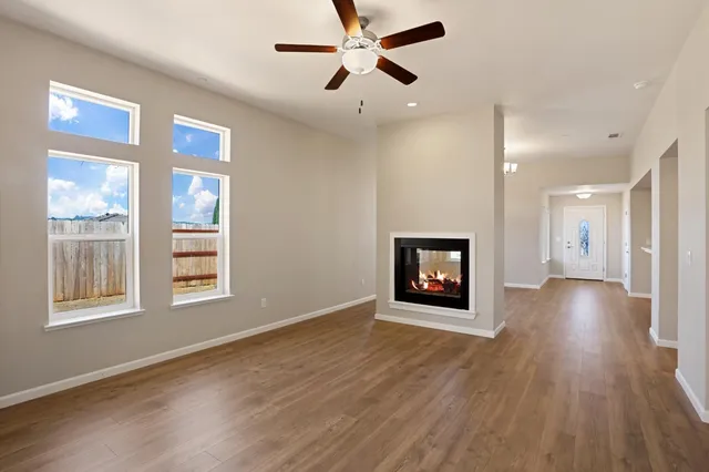 a view of an empty room with a window and wooden floor