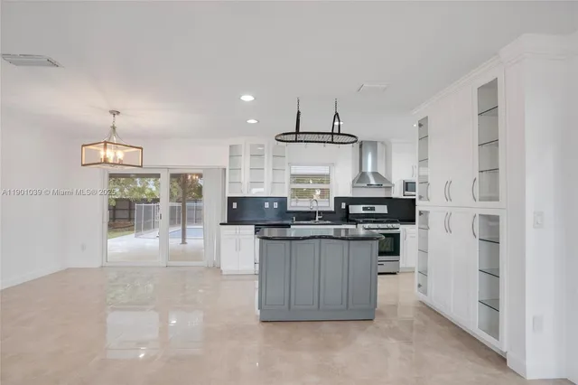 a kitchen with stainless steel appliances a sink a stove a refrigerator cabinets and a window